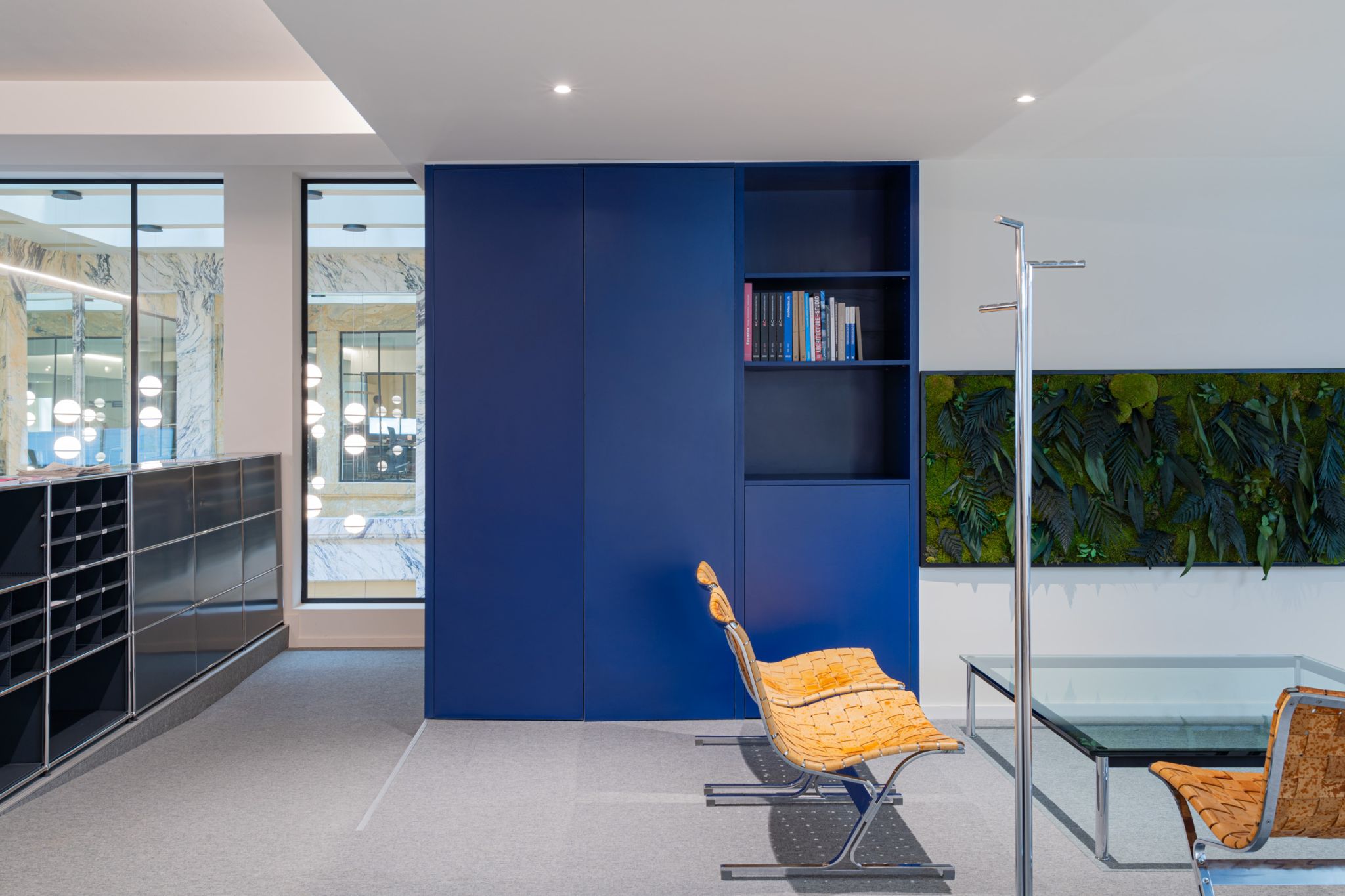 Espace de bureaux contemporain avec mobilier design, rangements intégrés et mur végétal favorisant un environnement de travail agréable.