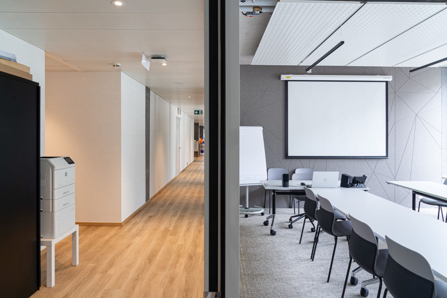Salle polyvalente aménagée avec écran de projection, mobilier modulable et accès direct aux circulations.