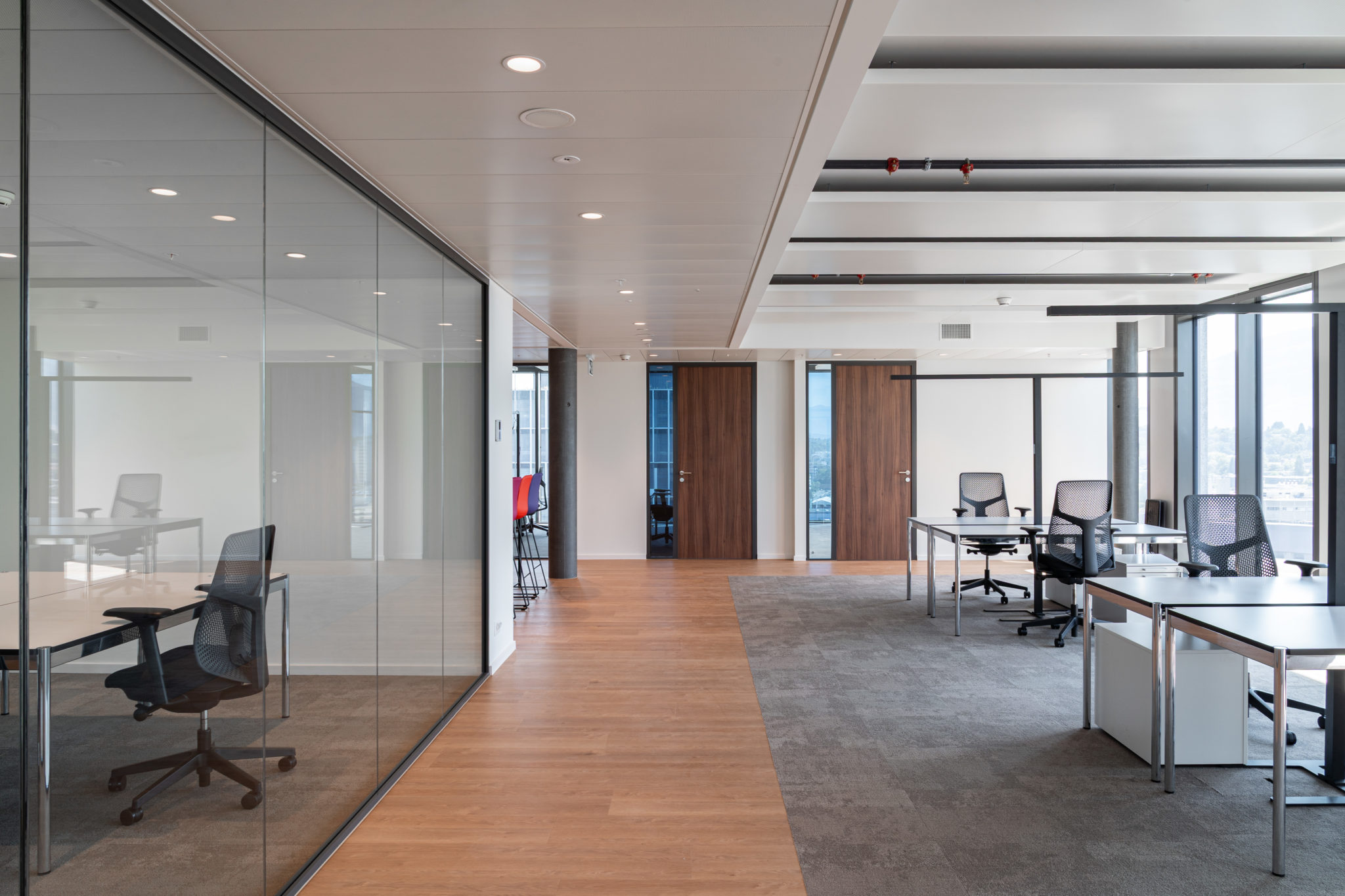 Open space contemporain avec bureaux, cloisons vitrées et circulation fluide entre les espaces.