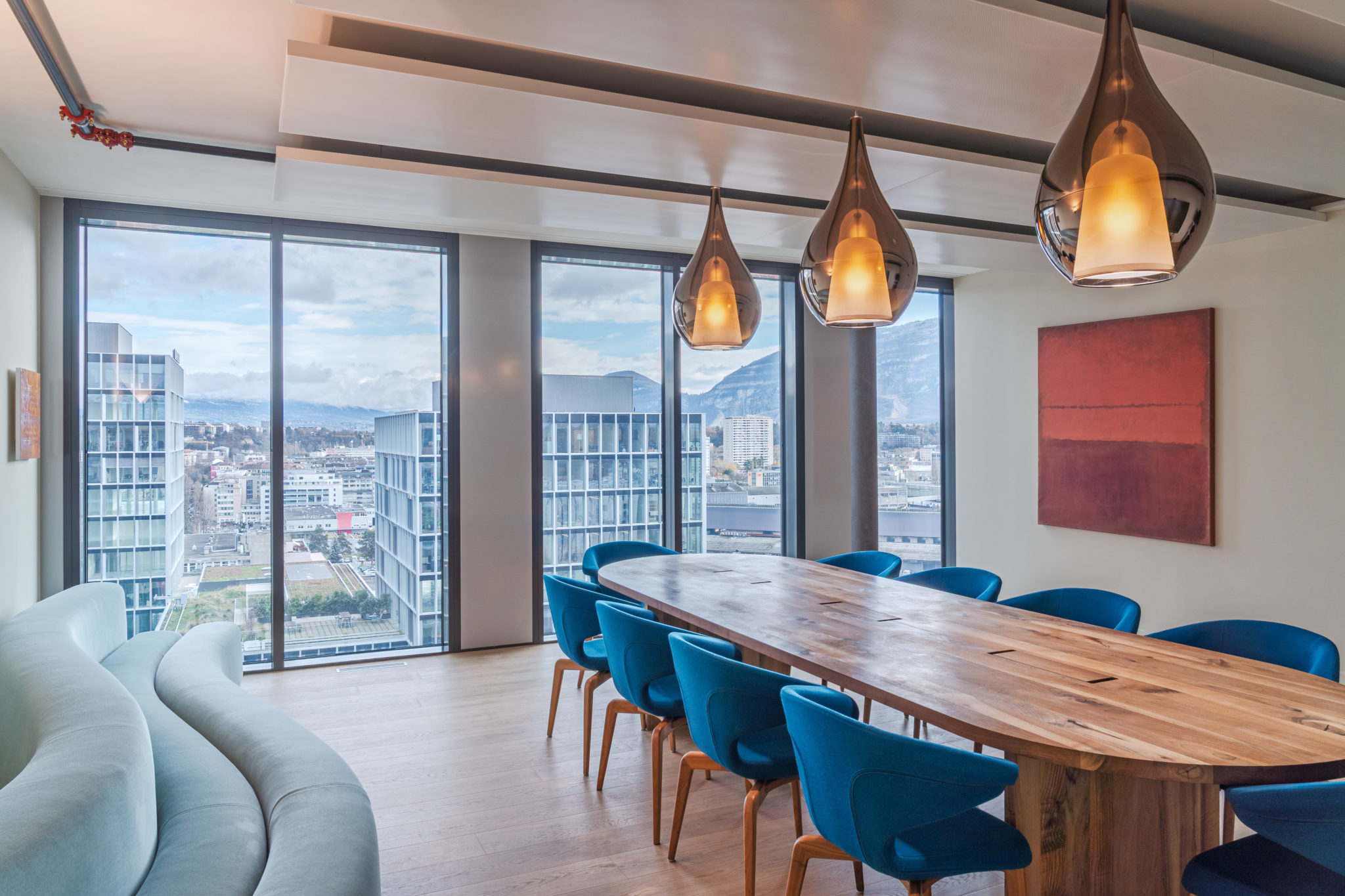 Salle de conférence contemporaine avec grande table en bois massif ouverte sur un panorama urbain.