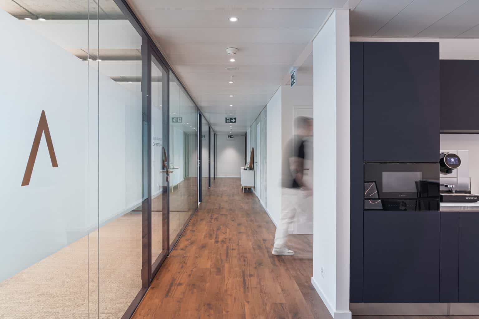 Espace de circulation entre les bureaux et la kitchenette dans des locaux professionnels modernes.