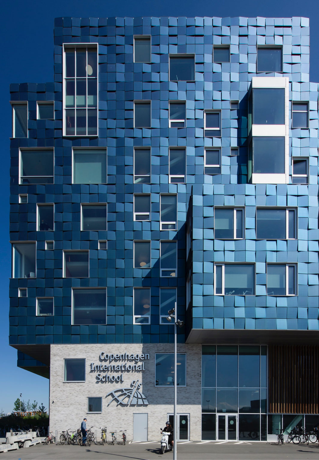 Façade moderne en verre composée de panneaux géométriques innovants, illustrant les avancées des matériaux utilisés dans la construction contemporaine.