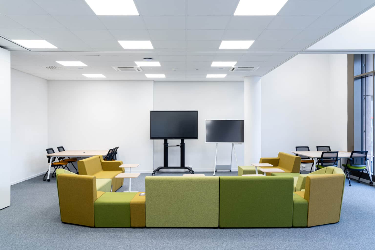 Salle collaborative équipée de mobilier modulable, écrans interactifs et espaces de travail en groupe.