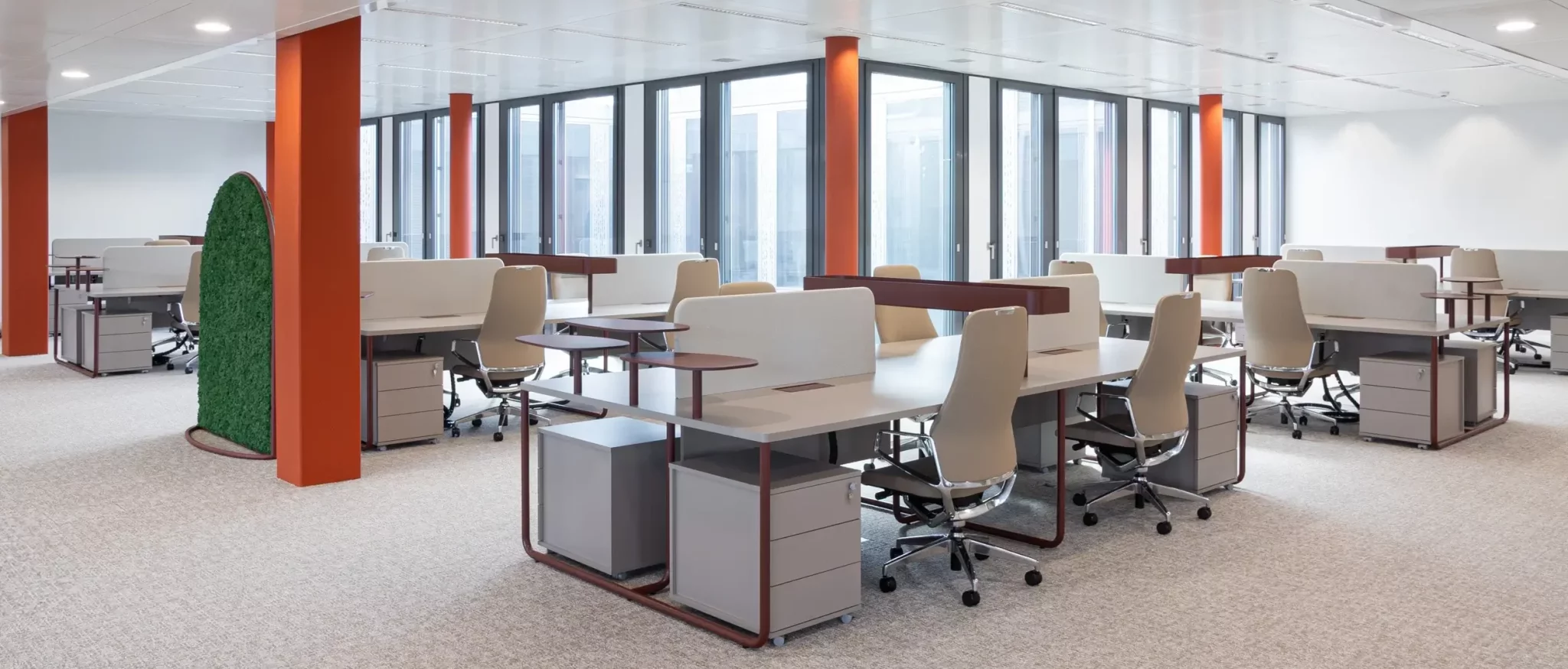 Grand espace de travail avec plusieurs bureaux, dans le fond lignée de baies vitrées