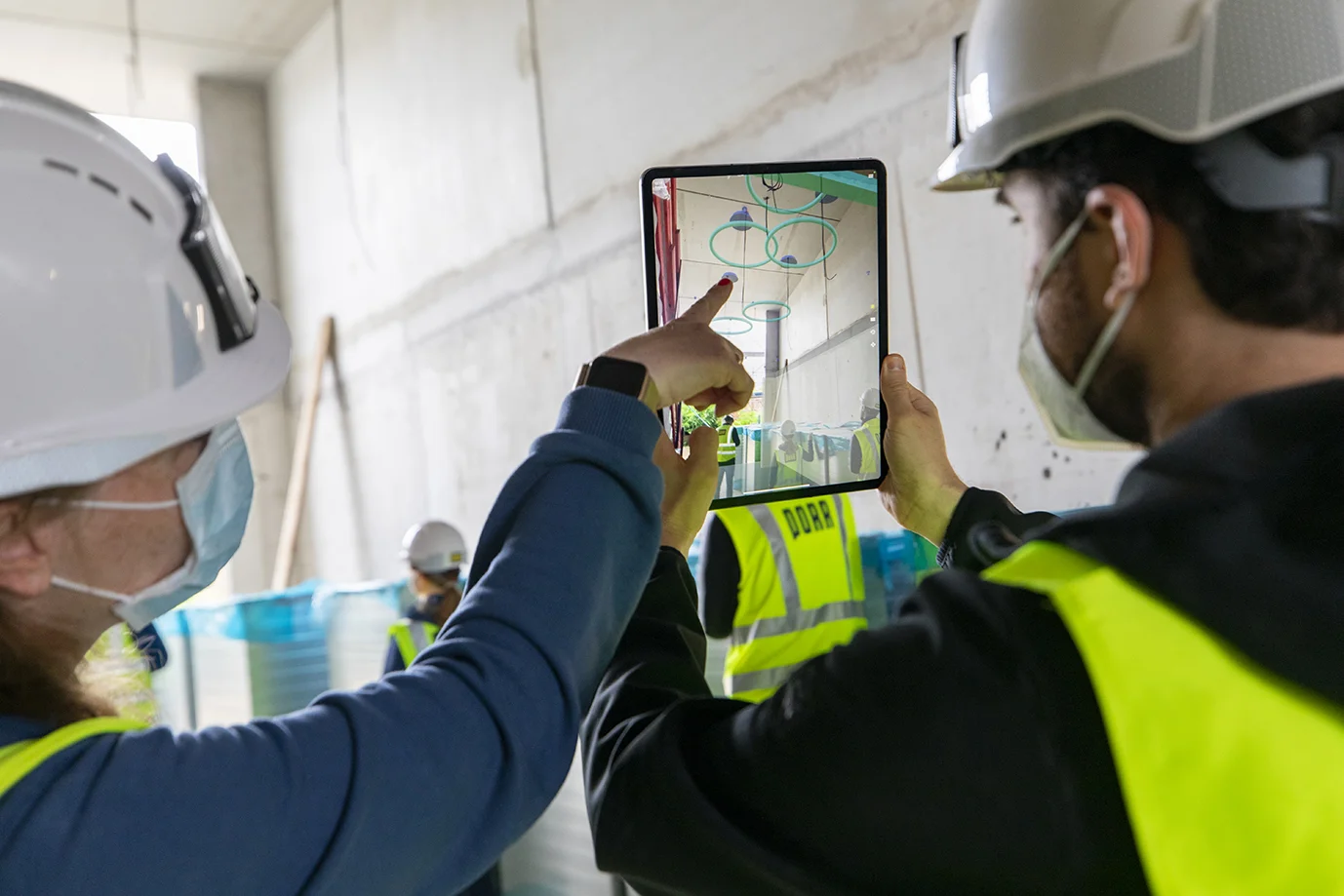 Professionnels du bâtiment consultant un modèle BIM sur tablette directement sur un chantier afin de comparer les informations numériques du projet avec l’avancement réel des travaux