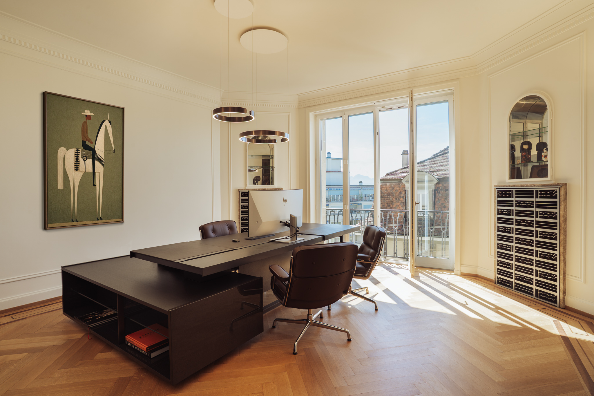 Bureau de direction Senzi, composé d’un grand plan de travail en bois, de fauteuils en cuir et de portes-fenêtres.